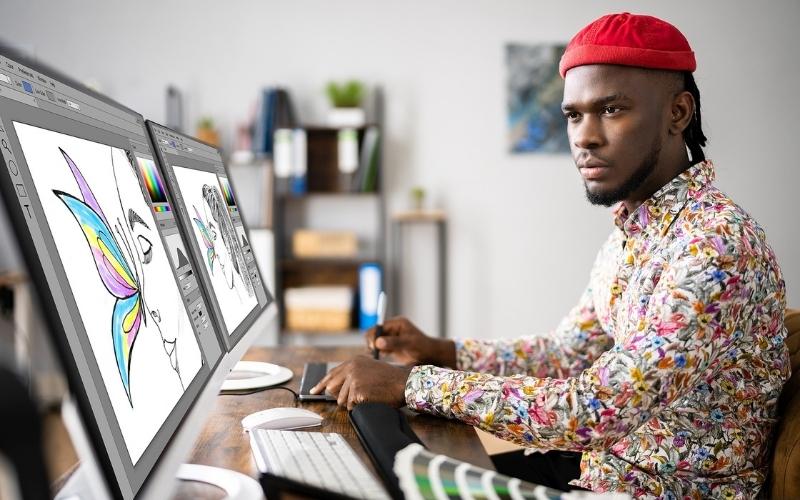 Man working on graphic designs on his duel monitors