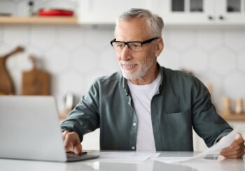 older man sitting at counter working on laptop